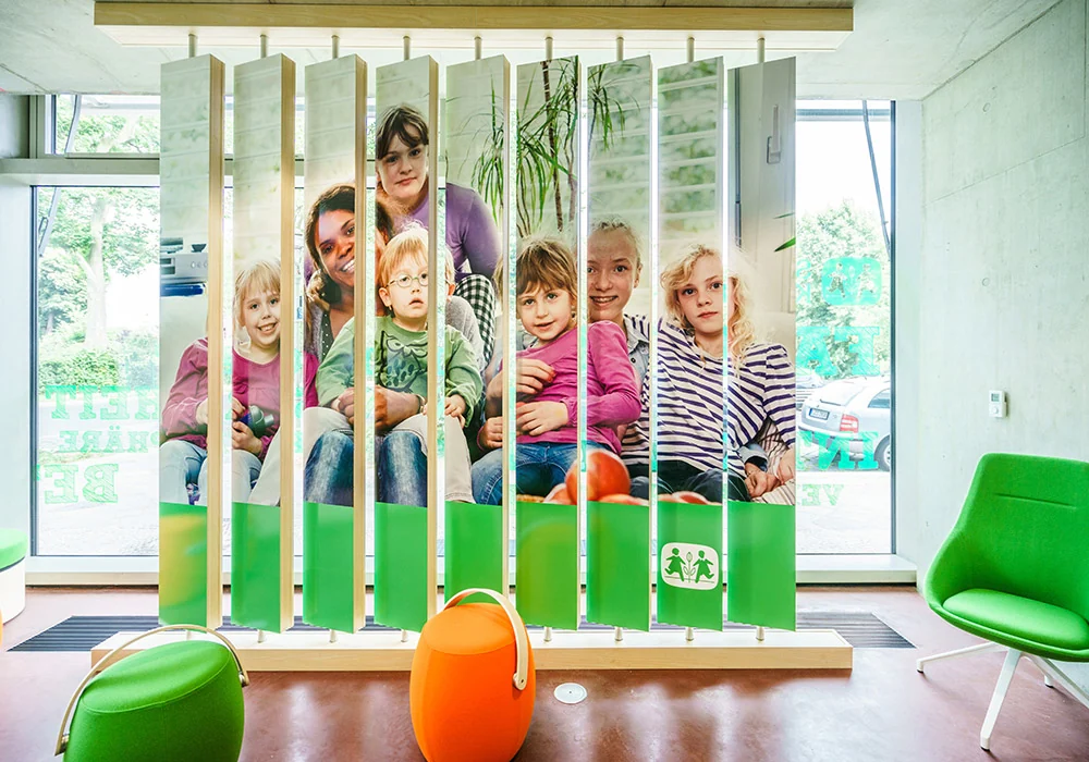 Lamellenwand mit Familienfoto in der Botschaft für Kinder von SOS-Kinderdorf