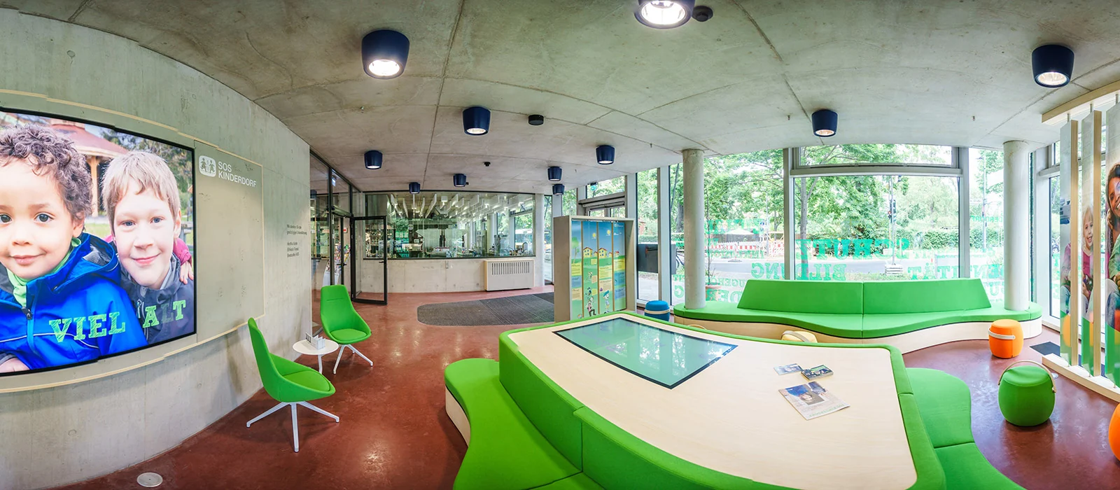 Innenraum der Botschaft für Kinder von SOS-Kinderdorf in Berlin-Moabit mit grüner Sitzlandschaft