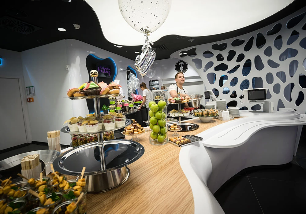 Buffet an der geschwungenen weißen Höhlenwand des World of Cyberobics