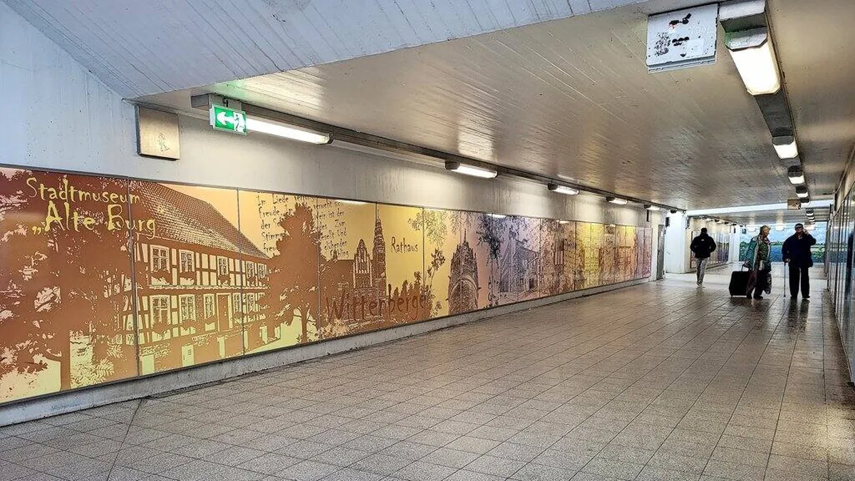 Goldene Wandgestaltung in der Bahnhofsunterführung Wittenberge mit Illustrationen von Stadtmuseum Alte Burg und Rathaus