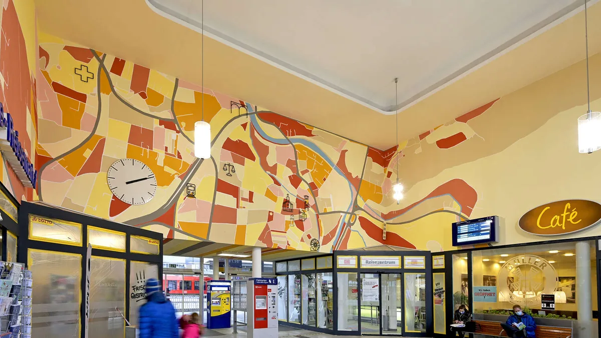 Konturgefräste Icons mit Abstandshaltern an der Wand der Bahnhofshalle Traunstein
